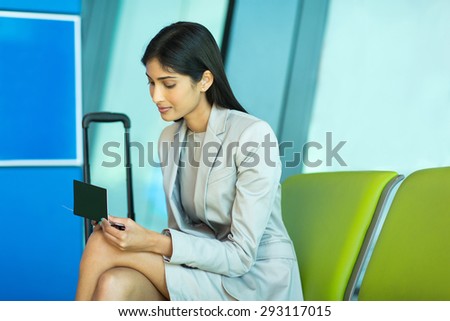attractive indian business woman looking at her air ticket at airport