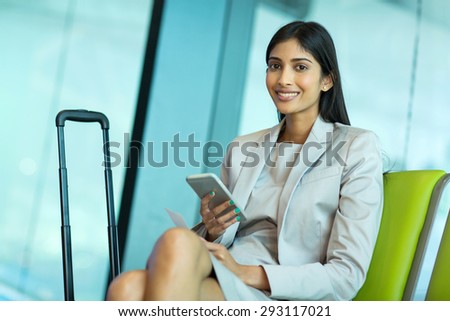 smiling indian businesswoman holding smart phone at airport