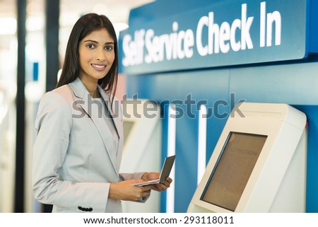 gorgeous indian businesswoman using self help check in machine at airport