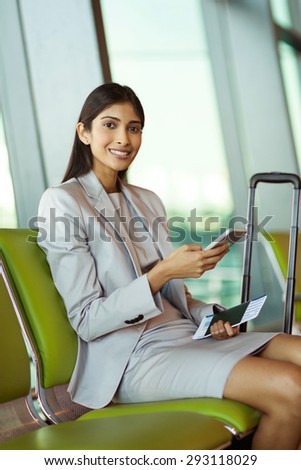 beautiful young indian businesswoman using cell phone at airport