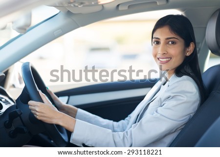 cheerful young indian businesswoman driving a car