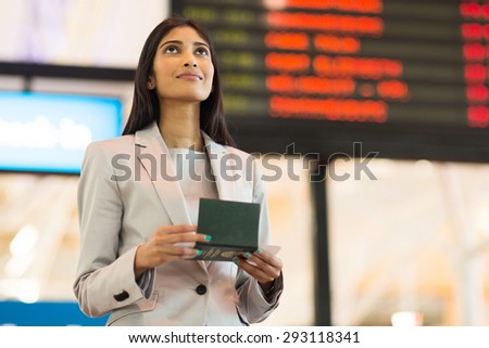 pretty indian business woman checking flight information at airport
