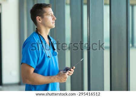 thoughtful male doctor holding tablet computer