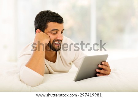 modern young indian man using tablet computer at home