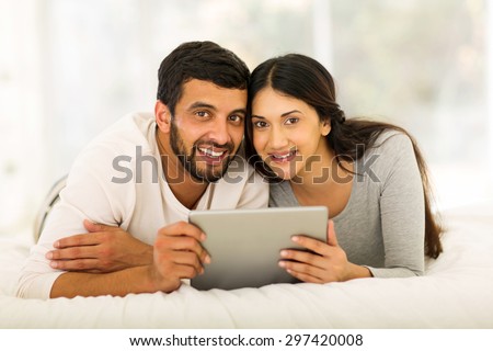 beautiful indian couple using tablet computer at home