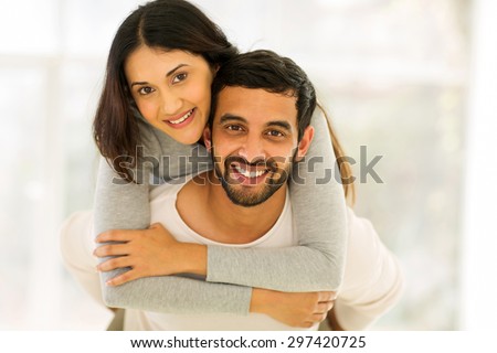 happy young indian couple having fun with piggyback indoors