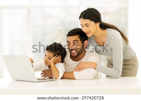 adorable young indian family using laptop at home
