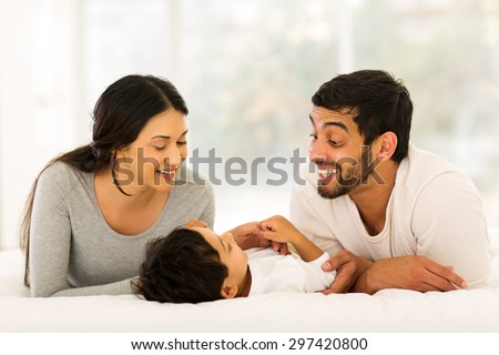 happy young indian family lying on bed