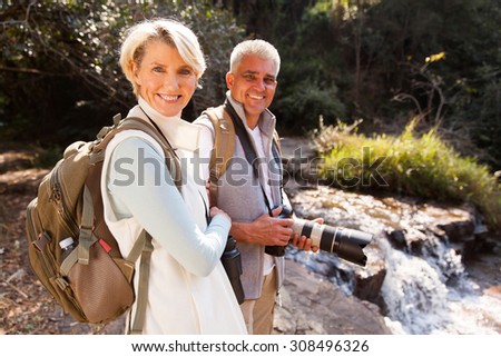 cheerful middle aged hikers relaxing by river enjoying outdoor activity