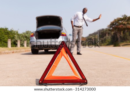 african man looking for help after a car breakdown at the side of the road