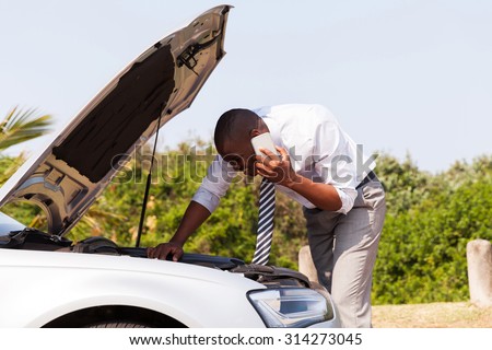 young man with broken down car with bonnet open calling for help