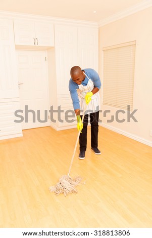 young african man mopping the floor in his empty apartment