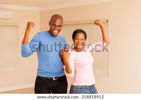 cheerful young african couple holding fist after buying a new apartment