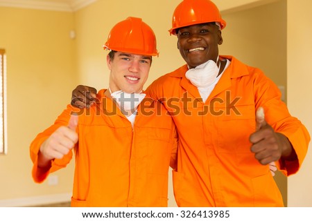 cheerful workmen giving thumbs up inside house