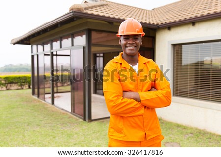 handsome african construction worker standing outside the house
