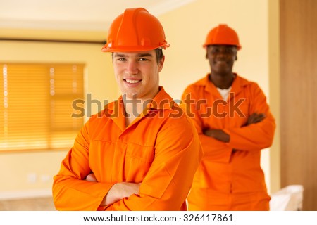 happy co-workers standing inside house under construction