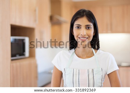 portrait of cute indian woman in kitchen with apron