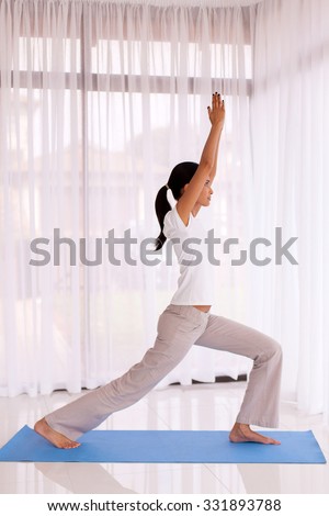 side view of fit indian woman doing yoga pose indoors