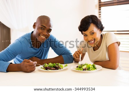portrait of young african american couple eating healthy salad for lunch