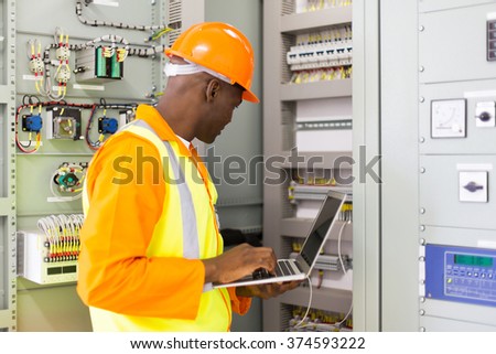 african american industrial engineer checking computerized machine status with laptop computer
