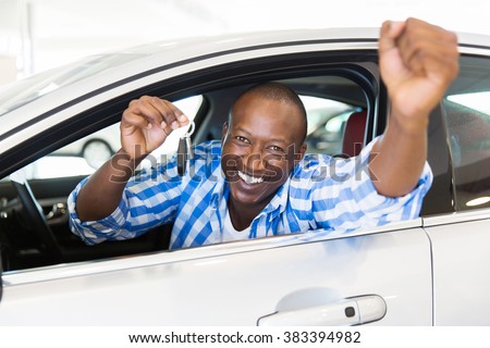 excited african man showing a car key inside his new vehicle