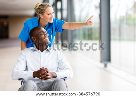 happy healthcare worker taking disabled patient for a walk in hospital