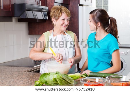 happy grandma talking to granddaughter in kitchen while cooking