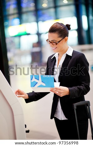 happy businesswoman using self help check in machine at airport
