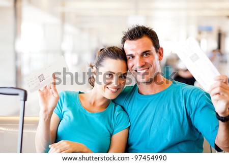 happy young couple with boarding pass at airport