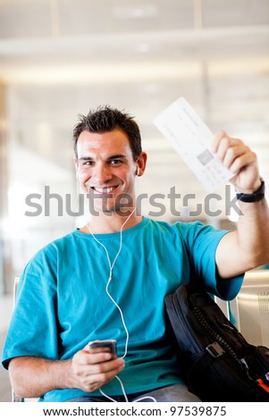 happy young man at airport with boarding pass