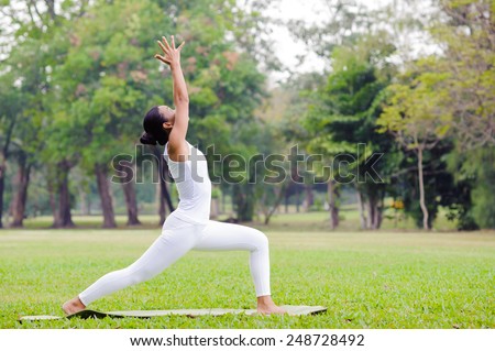 Beautiful woman practicing yoga in the park, High lunge pose.