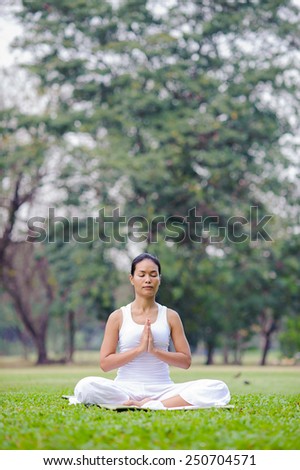 Beautiful woman practicing yoga in the park.Easy Pose / Sukhasana Meditation.