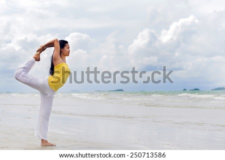 Young Asain woman practicing yoga on the beach and white cloud blue sky background