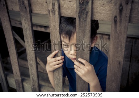 A boy standing behind a wood bar and hold it.