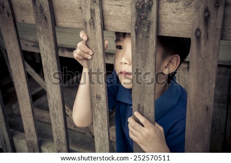 A boy standing behind a wood bar and hold it.