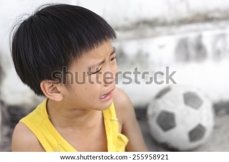 Young boy cry and tear during play football in front of concrete wall of concrete wall