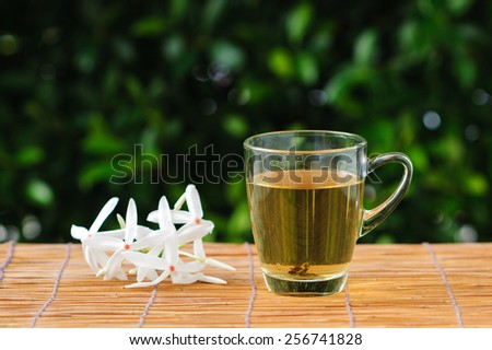 Hot herb tea in transparent glass on grass mat