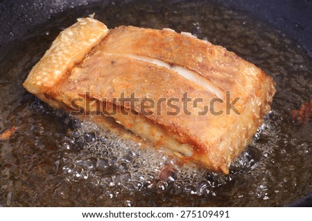 Fry fish Thai style food in hot oil in black pan