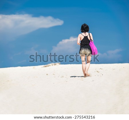 Girl carry pink bag walking alone on the white sand beach sunny day in Phuket Thailand