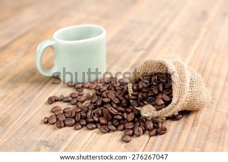 Close up thin focus on Coffee bean in bag and green cup on wood table