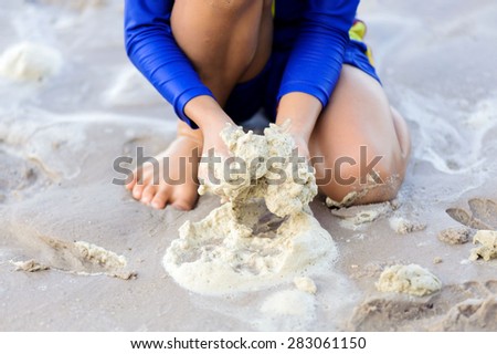 Boy hand play sea buble on the sand beach