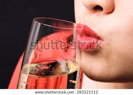 Close up focus on red lip Asian young woman kiss champagne on black background