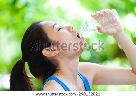 Portrait asian young girl drink water from plastic bottle on green bokeh