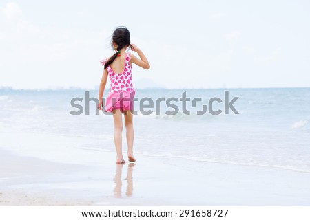 Little asian girl in pink walk on the beach sea side