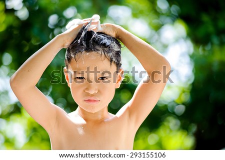 Asian boy washing hair by shampoo outside home under the daylight green bokeh from green tree