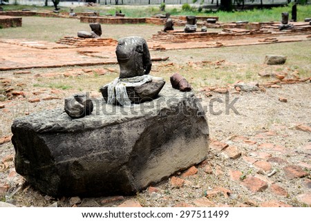 Budda statue in front of red brick pagoda in public area in Thailand without head because of thife .