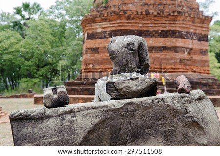 Budda statue in front of red brick pagoda in public area in Thailand without head because of thife .