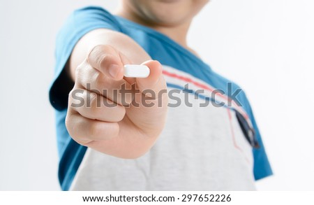 Close up on white tablet medicine in hand and blur face of young Asian boy on white background. Health care concept