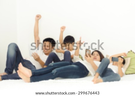 Out focus, Happy Asian family in living room using smartphone and tablet device each one separately. Social network concept.