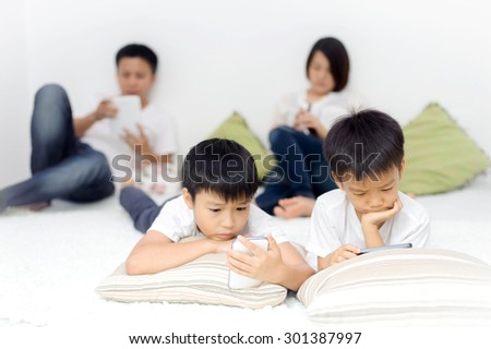 Family in living room using smartphone and tablet device each one separately. Social network concept.